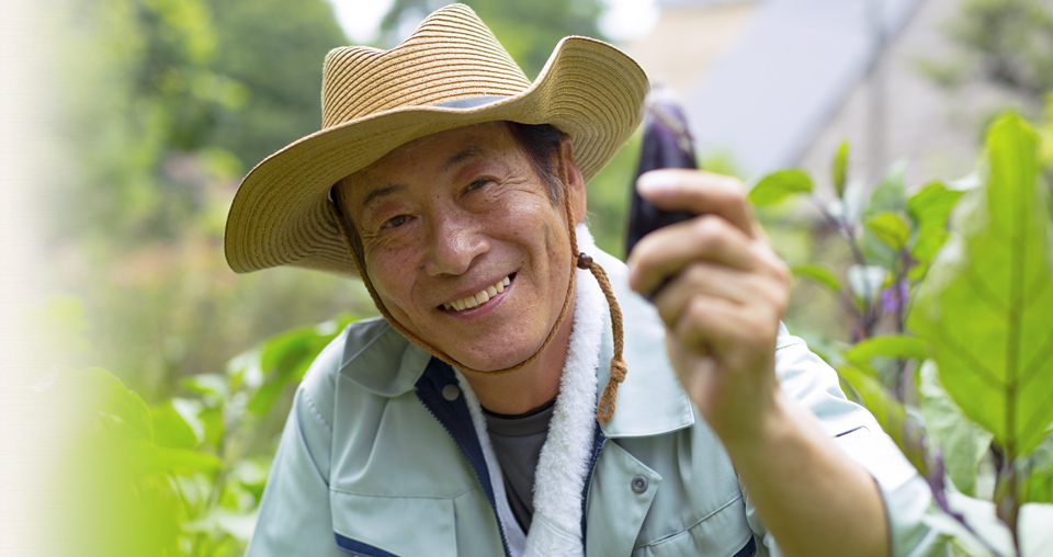 なすを持ち微笑む男性